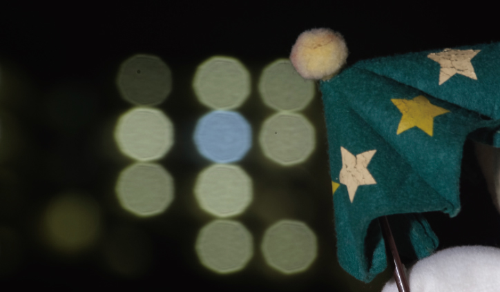 [photo] Green, cloth umbrella in foreground with blurred spherical lights in background