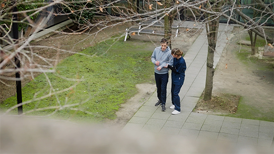 Man walking supported by female nurse