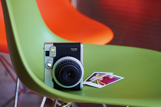 Black mini 90 camera with two photos on green chair