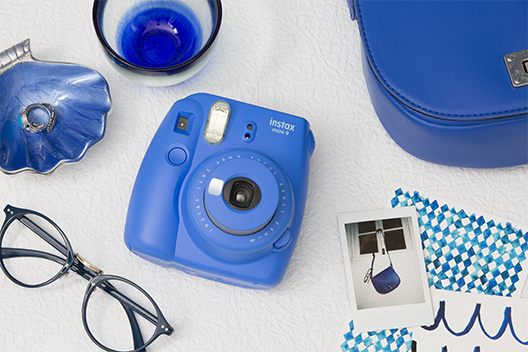 Image of blue Mini 9 camera on the table with other items in blue color
