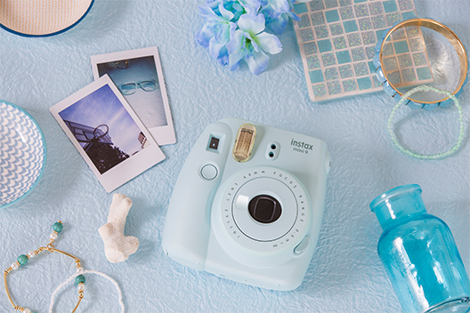 Image of Ice blue Mini 9 camera on the table with other items