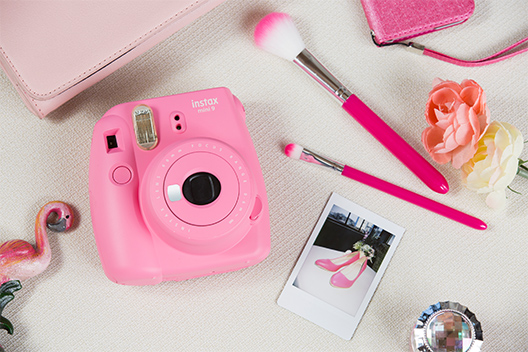 Image of Flamingo Pink Mini 9 camera on the table with other items in similar color