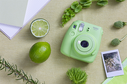 Image of Lime green Mini 9 camera on the table with other items in green color