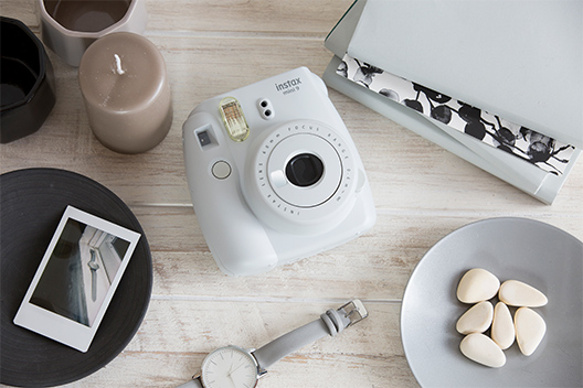 Image of Smoky White Mini 9 camera on the table with other items