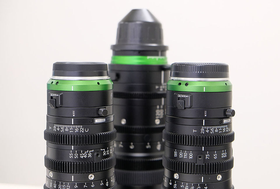 [photo] 3 Fujinon lenses with green ring and black alumite paint face down on a table