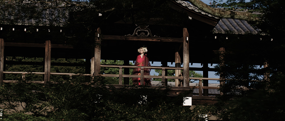 [photo] A very wide shot of a lady in traditional Japanese attire standing under a tradional Japanese wooden house