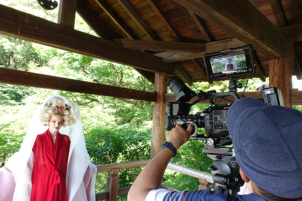 [photo] A film crew on set on location in Tokofuji, Kyoto shooting an actress dressed in traditional Japanese attire under a wooden roof