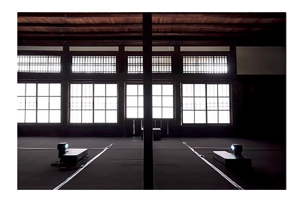 [photo] A big empty room with large windows and two projects at the center facing each other 