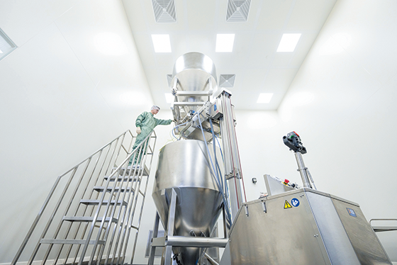 People working next to large tank equipment.